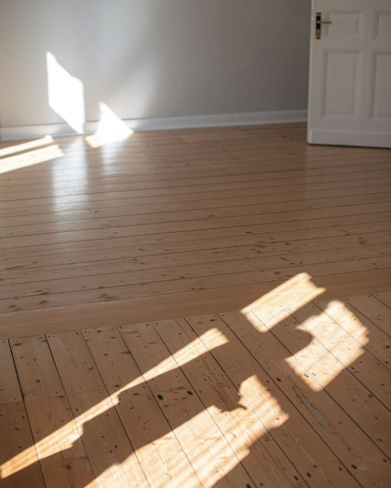 Leerer Raum mit Holzboden, Sonnenlicht und offener Tür